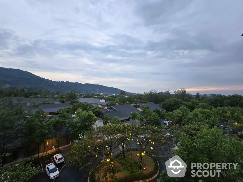 Scenic view of lush green landscape with residential buildings and mountains at dusk.