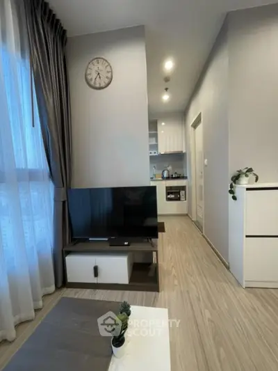 Modern living room with sleek design, featuring a wall-mounted TV, stylish furniture, and large window with curtains.