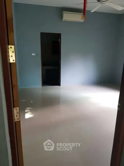 Spacious empty room with air conditioning and ceiling fan, ideal for customization.