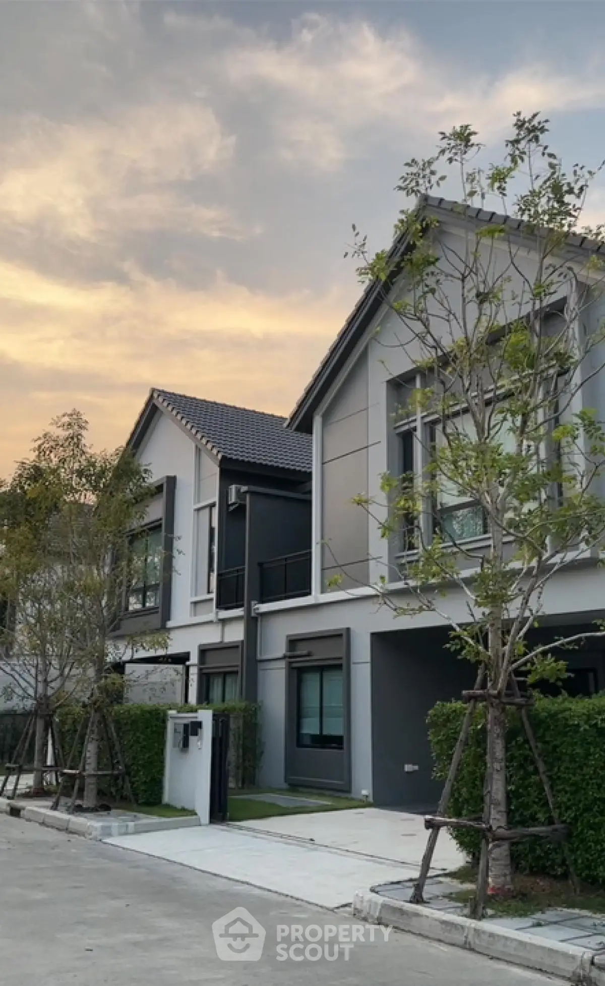 Modern two-story house with sleek design and lush greenery at sunset