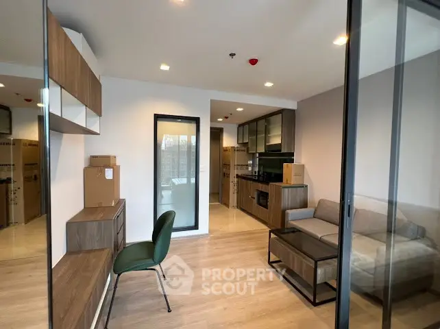 Modern living room with open kitchen, sleek furniture, and wooden flooring in a stylish apartment.