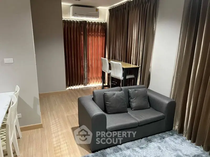 Modern living room with cozy sofa and dining area, featuring elegant curtains and wooden flooring.