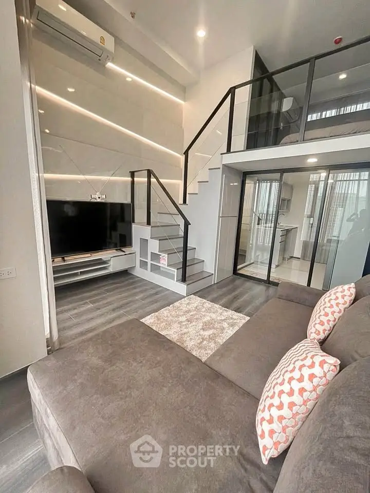 Modern loft-style living room with sleek staircase and cozy seating area.