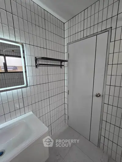 Modern bathroom with sleek tile design and illuminated mirror