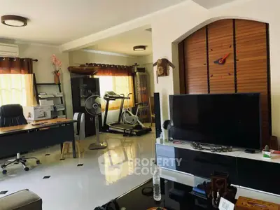 Spacious living room with modern decor, home office setup, and exercise equipment, perfect for work and relaxation.