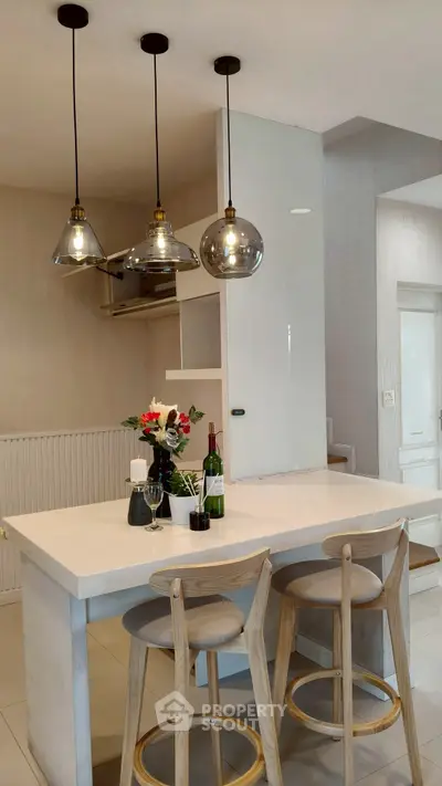 Modern kitchen with stylish pendant lights and breakfast bar seating