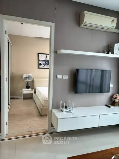 Modern living room with wall-mounted TV and view into cozy bedroom