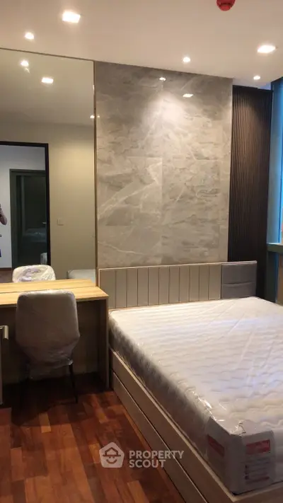 Modern bedroom with stylish decor and wooden flooring, featuring a cozy bed and a functional study desk.