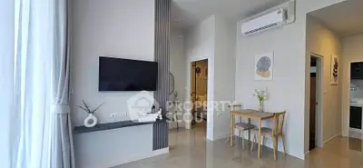 Modern living room with sleek TV setup and dining area in stylish apartment.