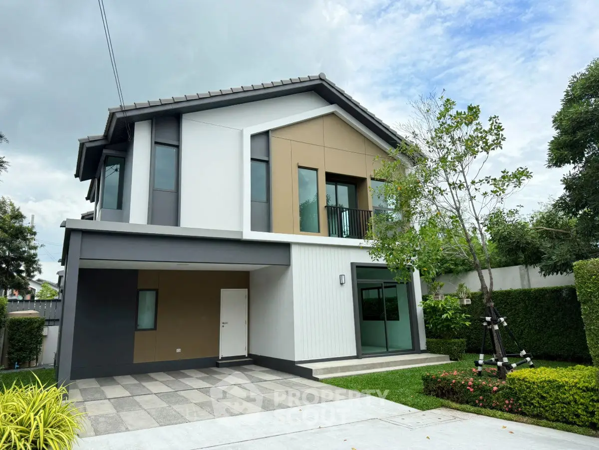 Modern two-story house with sleek design and spacious driveway in a lush green setting.