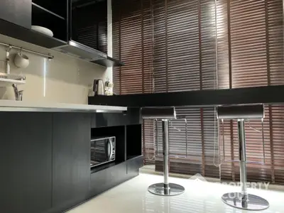 Modern kitchen with sleek black cabinets and stylish bar stools