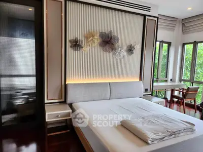 Luxurious bedroom with elegant decor and large windows offering a serene garden view.