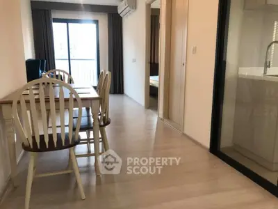 Modern apartment interior with dining area and balcony view, featuring sleek wooden flooring and bright natural light.