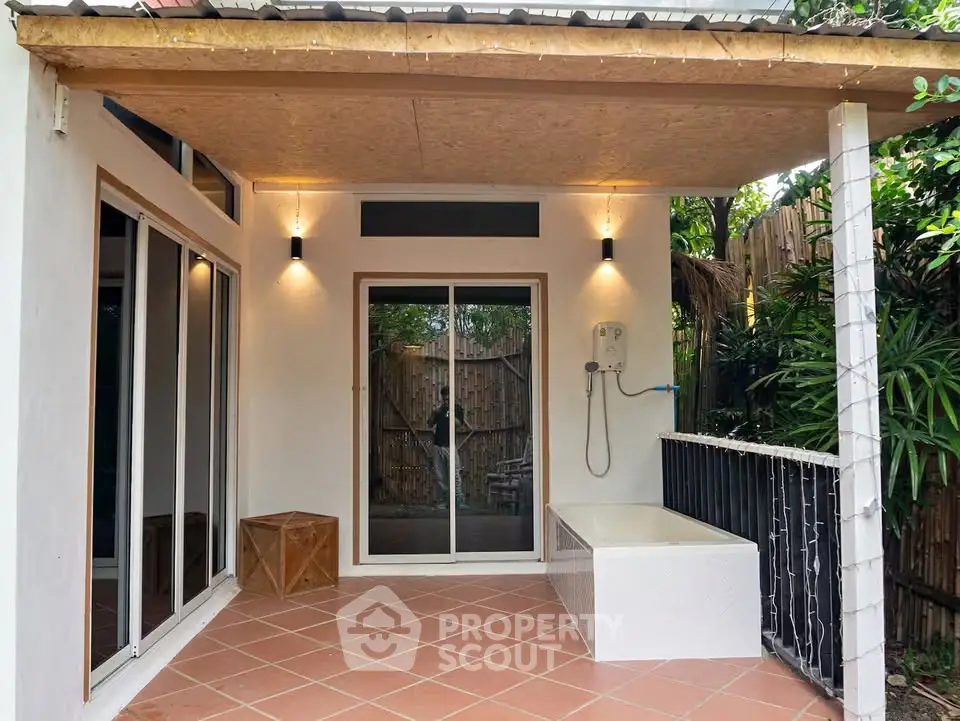 Charming outdoor patio with modern shower and cozy lighting, perfect for relaxation and entertaining.