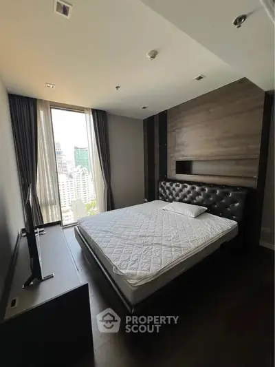 Modern bedroom with city view, featuring a stylish bed and large window.