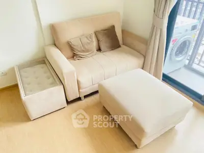 Cozy living room with beige sofa, ottoman, and washing machine by the window.
