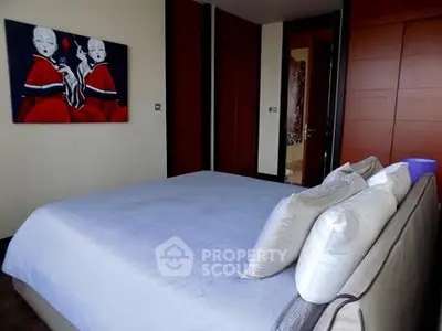 Modern bedroom with stylish decor and contemporary art on the wall.
