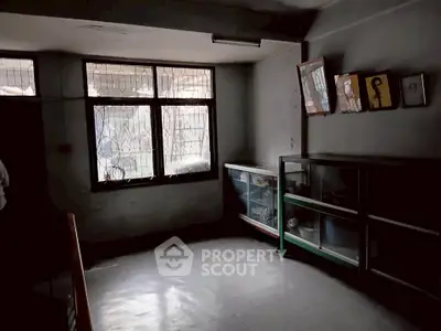 Dimly lit room with large windows and glass cabinets, ideal for storage or creative workspace.
