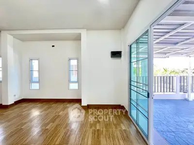 Spacious living room with wooden flooring and sliding glass doors leading to a covered balcony.