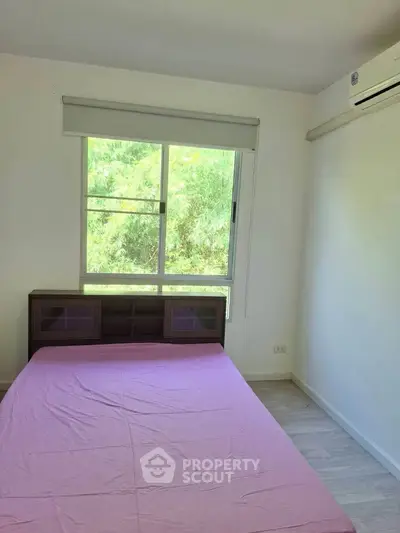 Cozy bedroom with large window and air conditioning, perfect for relaxation.
