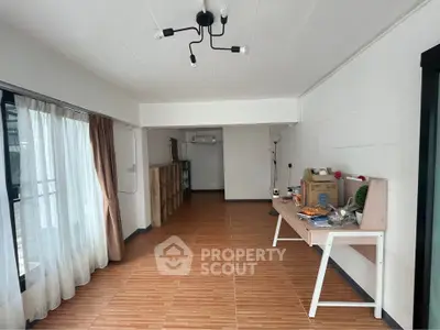 Spacious living room with wooden flooring and modern lighting, ideal for cozy gatherings.
