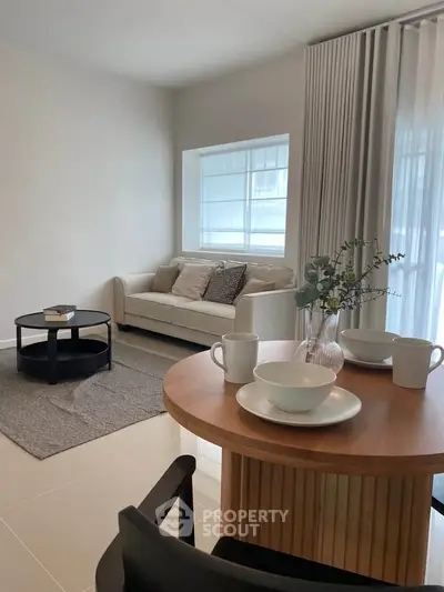 Modern living room with cozy sofa, stylish coffee table, and elegant dining setup in a bright, airy space.
