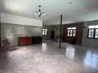 Spacious industrial-style living room with concrete floors and exposed brick walls.