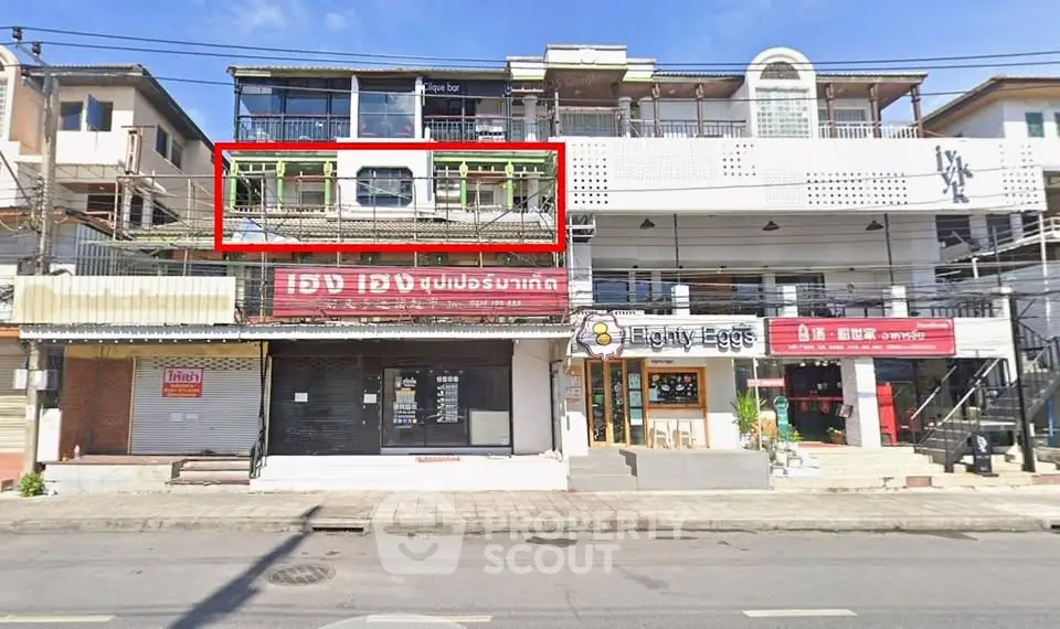 Commercial building exterior with multiple shops and signage on a sunny day.