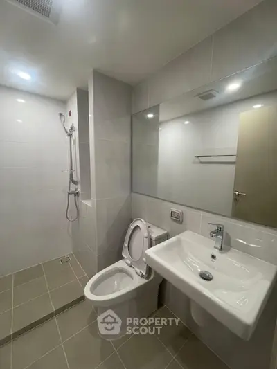 Modern bathroom with sleek fixtures and spacious shower area in a contemporary apartment.