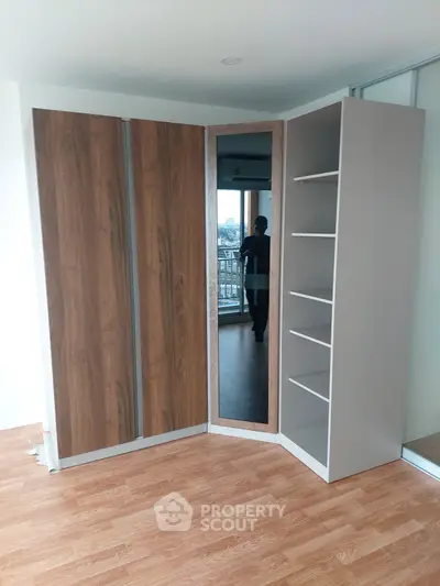 Spacious modern wardrobe with mirrored door in a bright room with wooden flooring.