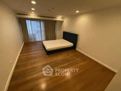 Spacious bedroom with wooden flooring and large window for natural light