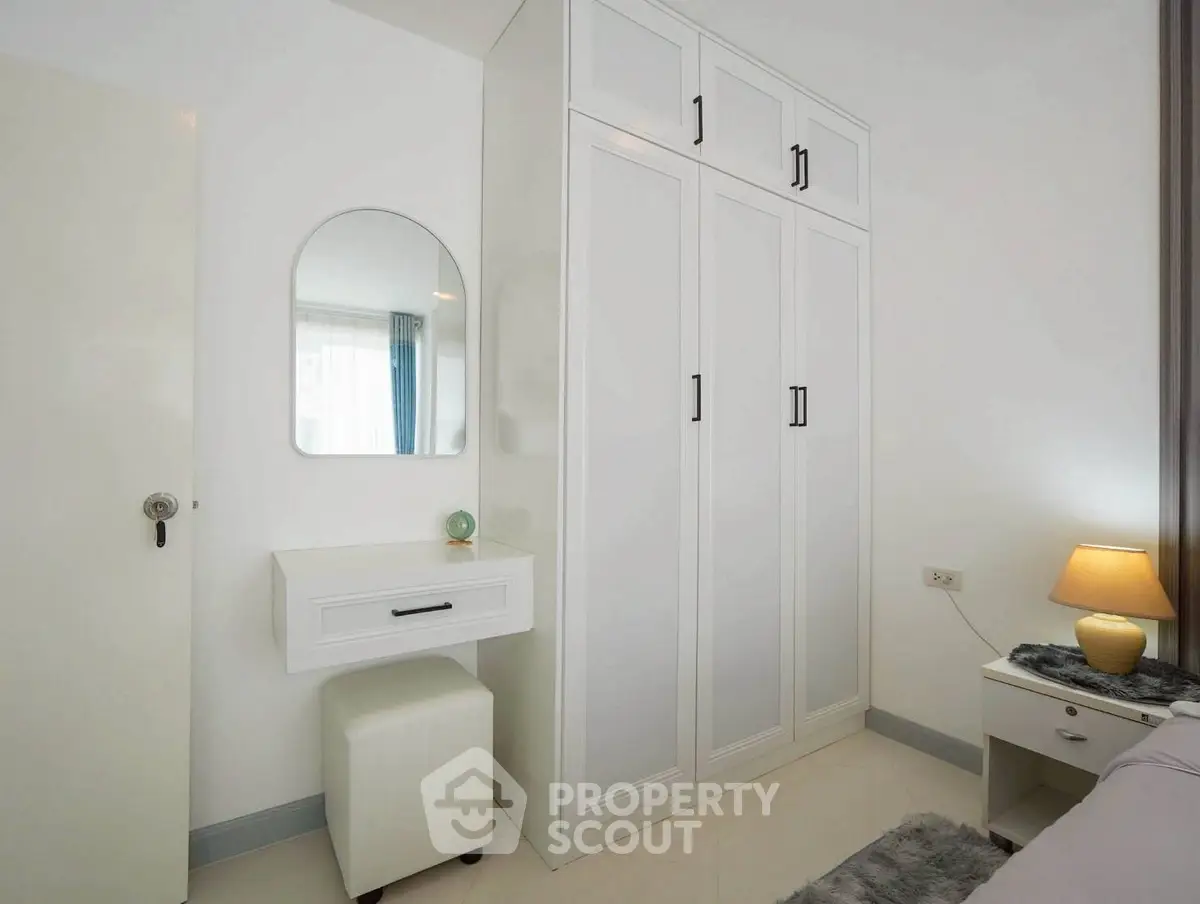 Chic bedroom with modern white wardrobe and stylish vanity in a cozy apartment.