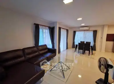 Spacious living room with modern furniture and dining area, featuring large windows and elegant curtains.