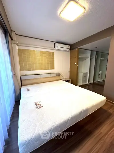 Spacious bedroom with mirrored wardrobe and modern air conditioning unit.