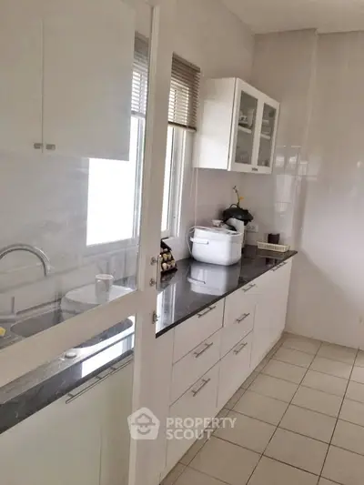 Modern kitchen with sleek white cabinets and ample counter space in a bright, airy setting.