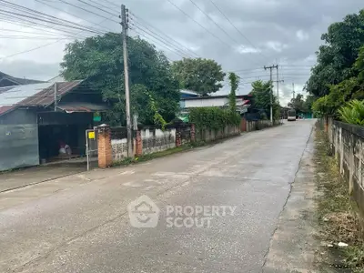Charming suburban street view with lush greenery and rustic homes, perfect for tranquil living.