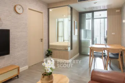 Modern living room with dining area and glass partition, featuring stylish decor and natural light.