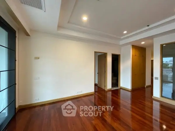 Spacious room with wooden flooring and recessed lighting, ideal for modern living.