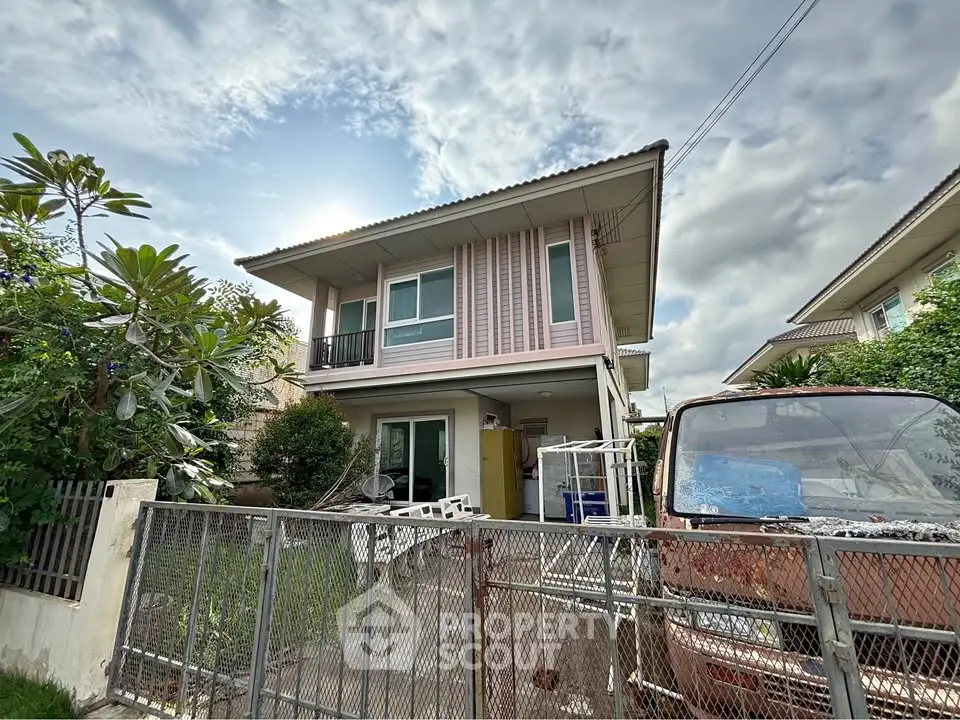 Charming two-story house with garden and gated entrance, perfect for family living.