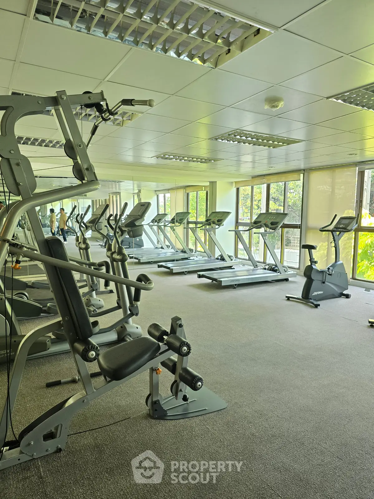 Spacious gym with modern exercise equipment and large windows for natural light.