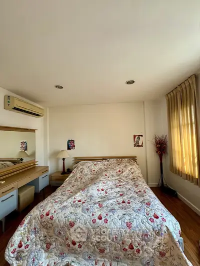 Cozy bedroom with floral bedding and natural light, featuring a stylish dresser and elegant curtains.