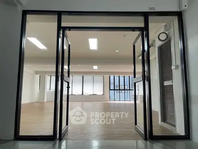 Spacious modern office space with large windows and wooden flooring.