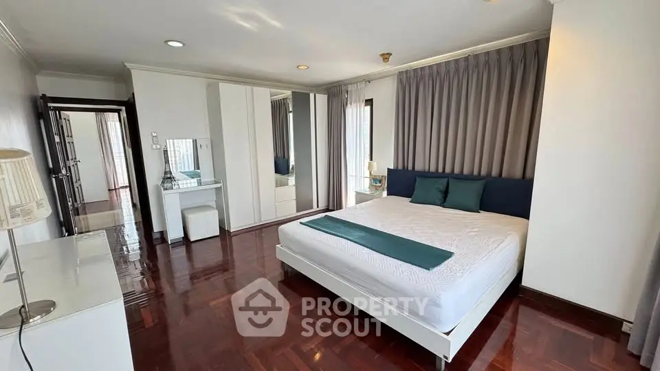 Spacious bedroom with elegant decor and large windows in a modern apartment.