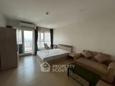Spacious studio apartment with modern furnishings and city view balcony.