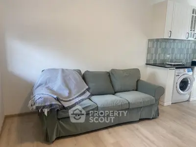 Cozy living room with a comfortable sofa and modern kitchen appliances.