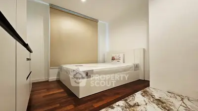 Modern minimalist bedroom with wooden flooring and sleek white furniture