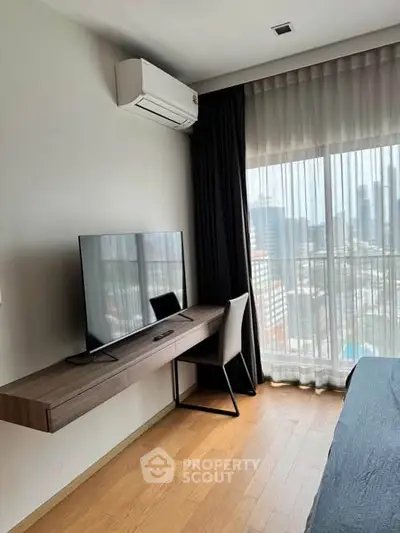 Modern bedroom with city view, featuring sleek desk, TV, and air conditioning.