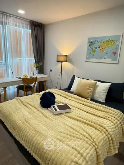 Cozy bedroom with modern decor and natural light, featuring a stylish workspace and comfortable bedding.
