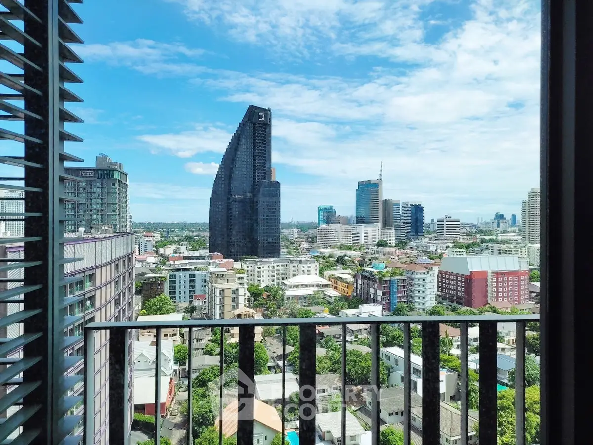 Stunning cityscape view from a high-rise balcony with modern architecture and blue sky.
