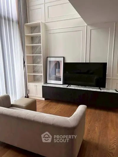 Luxurious living room with elegant decor and large TV, featuring hardwood floors and stylish shelving.